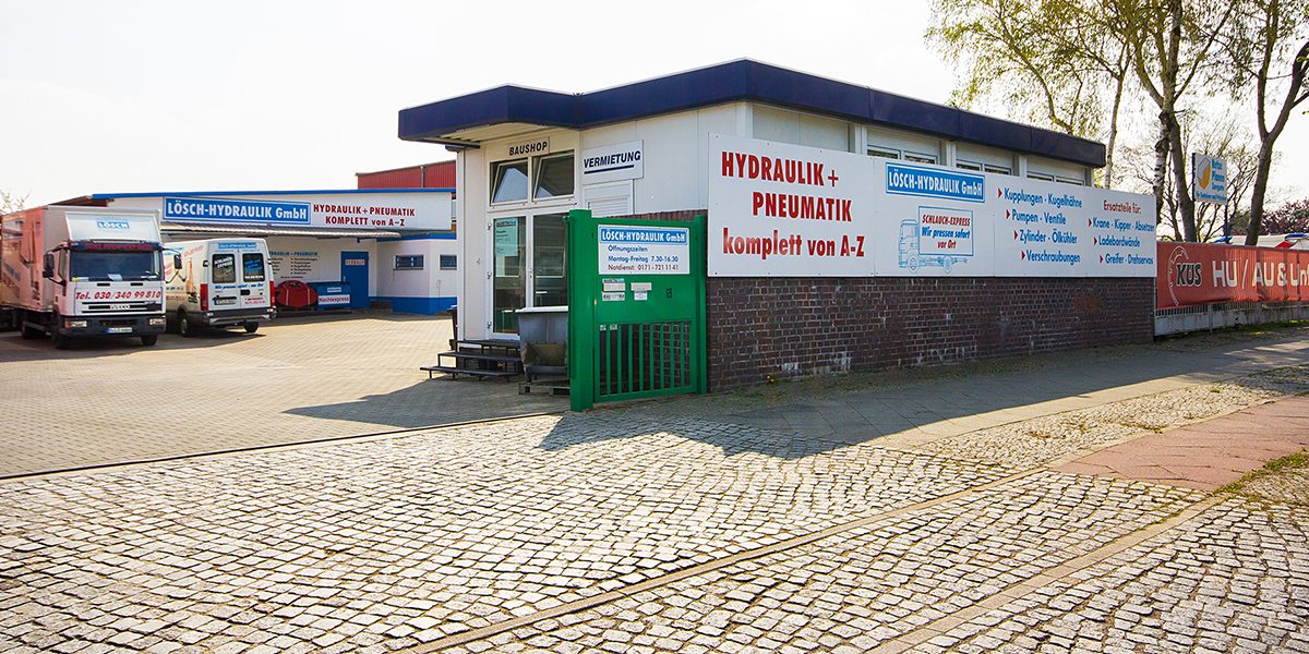 Firmengelände der Lösch-Hydraulik GmbH am Saatwinkler Damm 69 in Berlin: Ladengeschäft mit der Aufschrift „Hydraulik + Pneumatik komplett von A–Z“, daneben Lkw und Transporter
