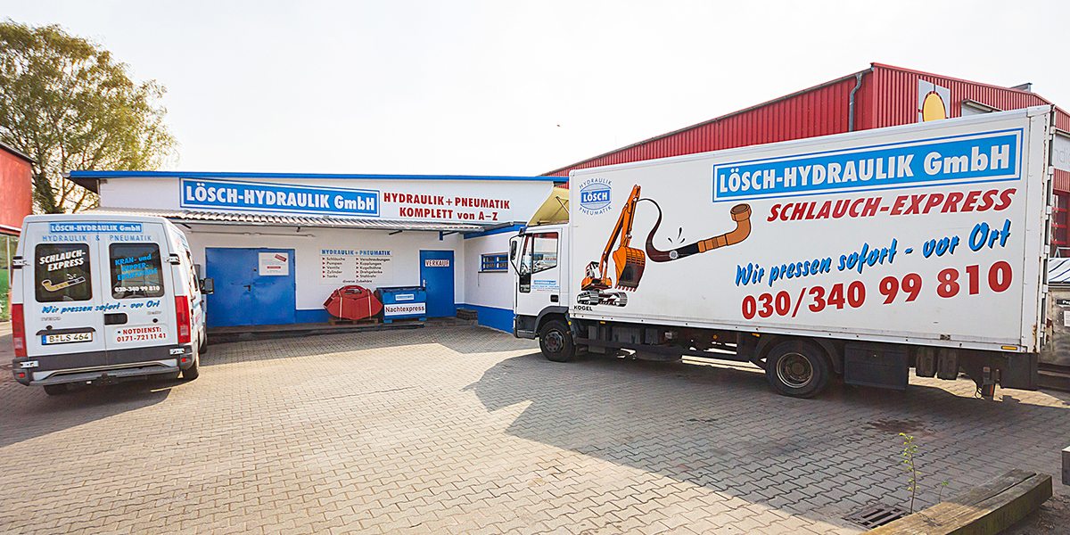 Hof der Lösch-Hydraulik GmbH mit Ladengeschäft, Servicetransporter und Schlauchexpress-Lkw mit der Aufschrift „Wir pressen sofort – vor Ort“