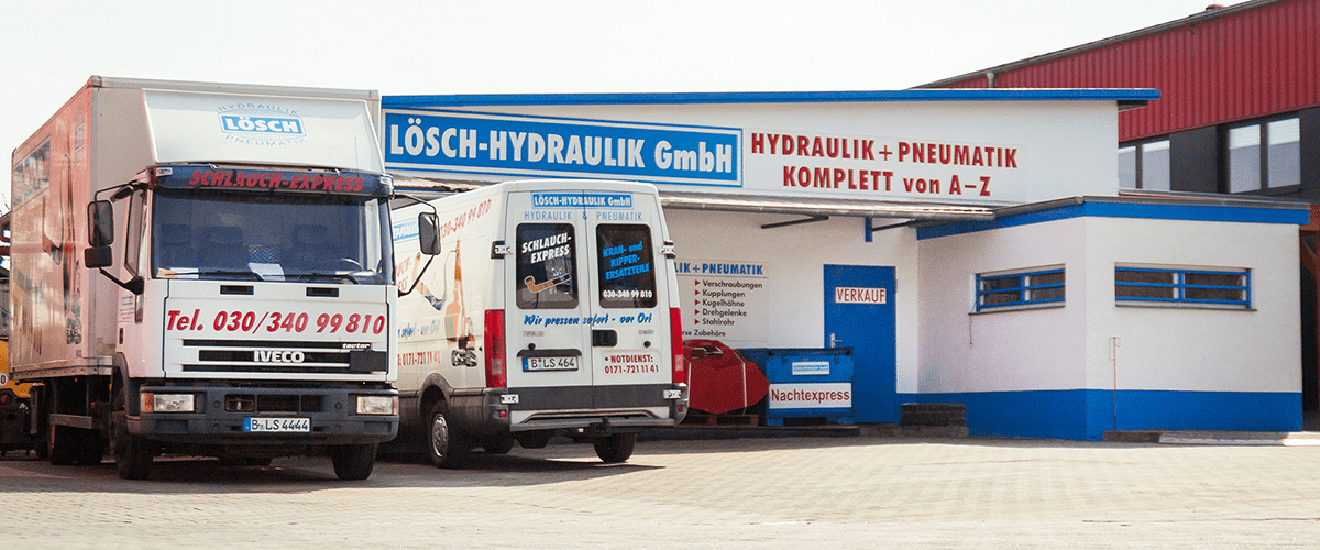 Ladengeschäft der Lösch-Hydraulik GmbH mit dem Schild „Hydraulik + Pneumatik komplett von A–Z“, davor Schlauchexpress-Lkw und Servicetransporter
